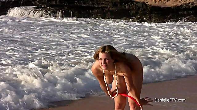 Curvaceous girl in a red bikini shows her nude body on the beach