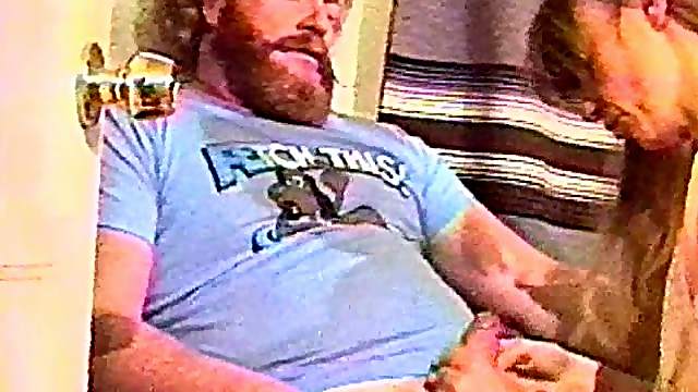 Two guys service a burly guy with a beard in a homemade video