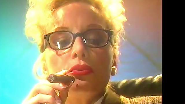 Blonde mature lady with glasses smokes a cigar and plays with her tits