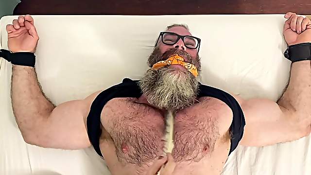 Muscular older dude tied up to a bed and licked by his best friend