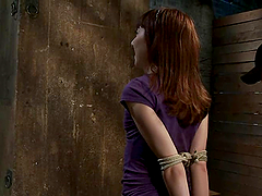 Bound Emma Haize sits on a the floor and gets toyed