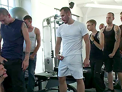 A tied up guy sucks huge dicks and get toyed in a gym